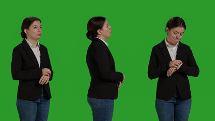 Obraz premium Close up of impatient office worker checking time on wristwatch, standing over isolated greenscreen backdrop. Young woman running late and looking at clock, waiting for something,