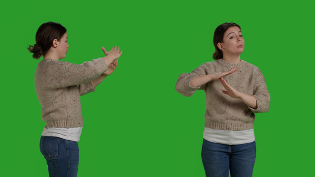 Caucasian woman doing t shape symbol with hands, showing refusal and no sign over greenscreen backdrop. Negative bored girl expressing timeout or break gesture, rejection and disapproval.
