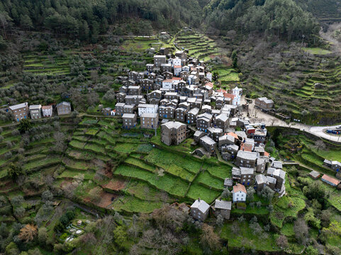 Aerial view of Piodao's schist houses nestled on terraced slopes, a rustic tapestry woven into the rugged landscape, Piodao, Arganil, Portugal.