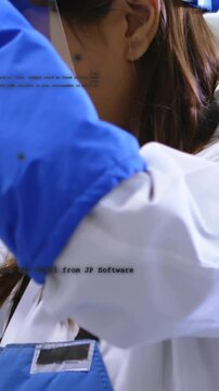Vertical video: Lab tech leaning at bench with face shield as gloved arm crossing, handling sample