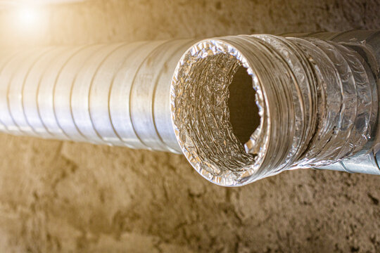 A close-up view of a dirty air vent and flexible duct attached to a building's ceiling. The vent shows signs of significant dust and grime accumulation.