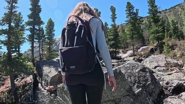 Mountain travel in Russia. Altai Republic, Multinsky Lakes. First-person view, a journey to the lakes over rocks. A couple walking over rocks with backpacks.