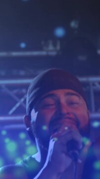Vertical video: Camera moving in on singer, particles drifting across face while performing music