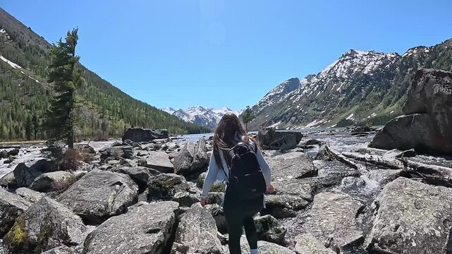Mountain travel in Russia. Altai Republic, Multinsky Lakes. First-person view, a journey to the lakes over rocks. A couple walking over rocks with backpacks.