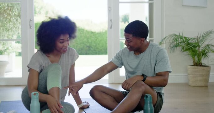 African American couple showing phone laughing pointing opening reusable bottles to hydrate at home