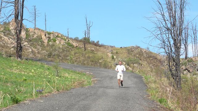 A man runs on a mountain slope. Seminsky Pass. A man runs down a hill in the morning. Summer biathlete training.