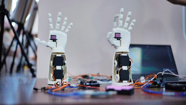 3D printing robot hand prototypes at a robotics exhibition, showcasing engineering innovation