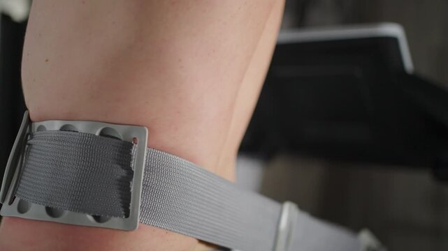 Close-up of Man Using Anti-Cellulite Belt Trainer. A person wearing massage belt for body shaping and cellulite reduction. Fitness massager used on the waist for weight loss and wellness