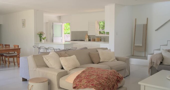 Slow cam panning right, revealing beige sectional with red throw, showing open plan layout for sale