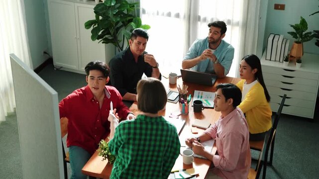 Top view of leader standing and present idea at whiteboard. Group of diverse people listen presentation. Team looking at leader talking about plan while colleague helping to explain idea. Convocation.