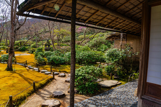 The traditional Japanese tea house veranda of Okochi Sanso villa in Arashiya framing a serene moss garden with a stepping-stone path, stone lantern and manicured shrubs, evoking calm and relax
