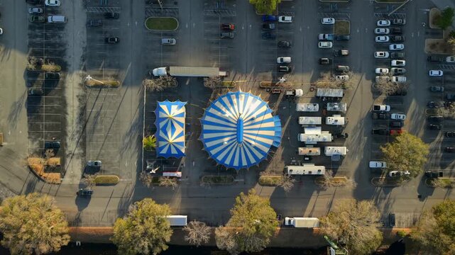 Aerial view of blue and white striped circus tents and trailers create a striking pattern against the asphalt, St. Augustine, Florida, United States.