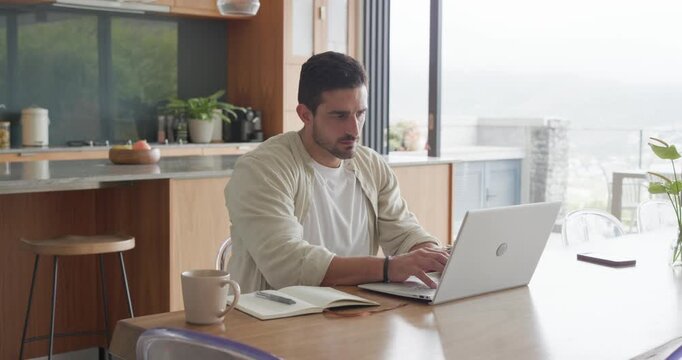 Man in open shirt starting session on laptop at kitchen table, typing, stretching, finishing report