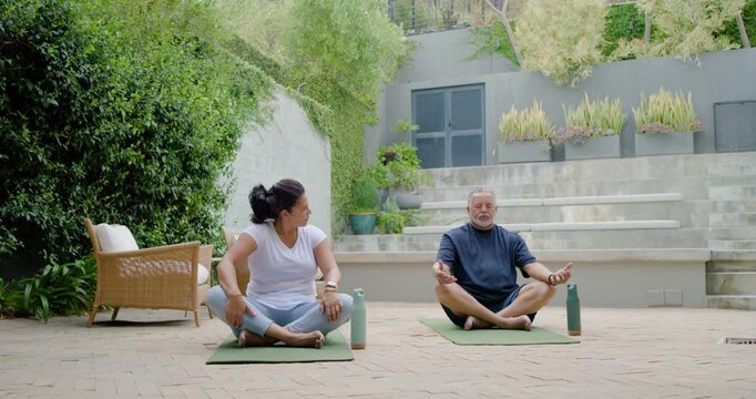 Woman turning toward man is initiating dialogue while man is gesturing on green mats, walled garden