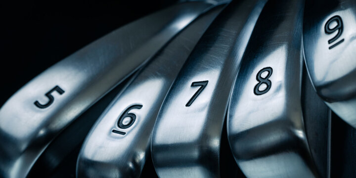 Close up of iron golf club heads on dark background