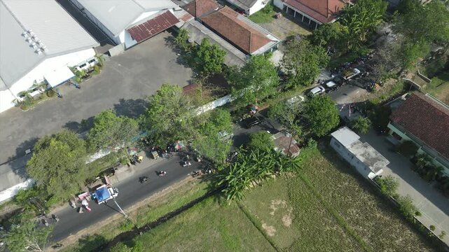 Aerial view of a busy village street with houses and rice fields in Indonesia, 4K footage.