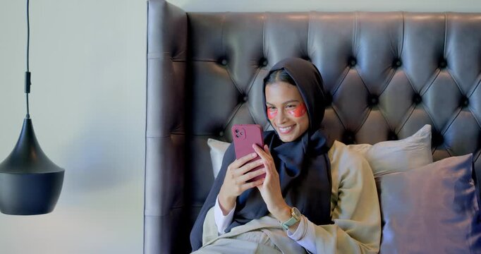 African American woman receiving alert, checking pink phone, adjusting red eye patches, smiling