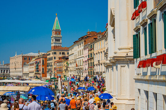 Venice, Italy - 29 March 2026: View of the bustling Riva degli Schiavoni crowded with tourists, the Campanile di San Marco piercing the azure sky.