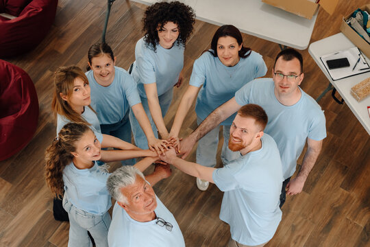 Diverse volunteers stacking hands showing teamwork solidarity