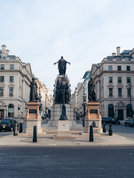 London, United Kingdom - 20 June 2025: View of the Crimean War Memorial stands tall, its bronze figures a solemn contrast to the pale stone buildings lining the wide, sun-drenched street.