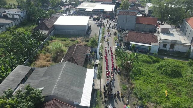Aerial view of a busy village street with houses and rice fields in Indonesia, 4K footage.