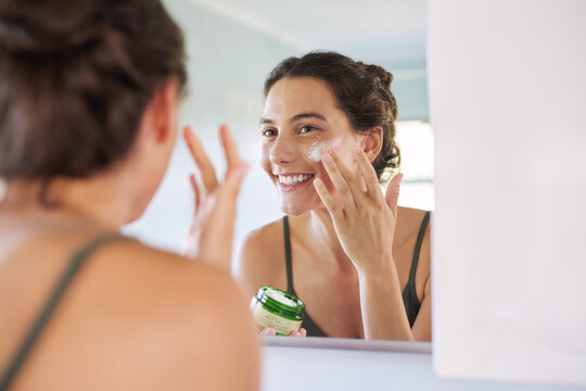 Happy smiling woman applying moisturizer lotion in the morning