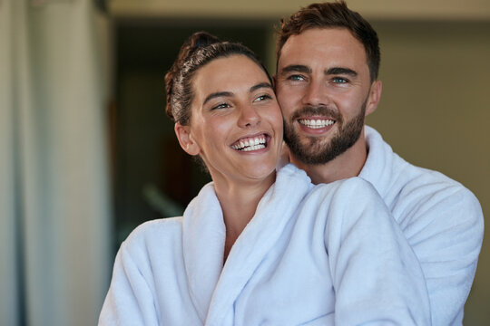 Happy mid adult couple hugging in bathrobe at spa