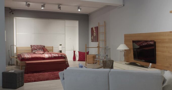 Modern bedroom and living area interior with red bed linen and wooden furniture in a showroom