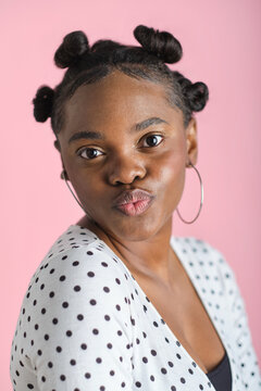 headshot portrait of Young black woman pouting wearing bantu knots