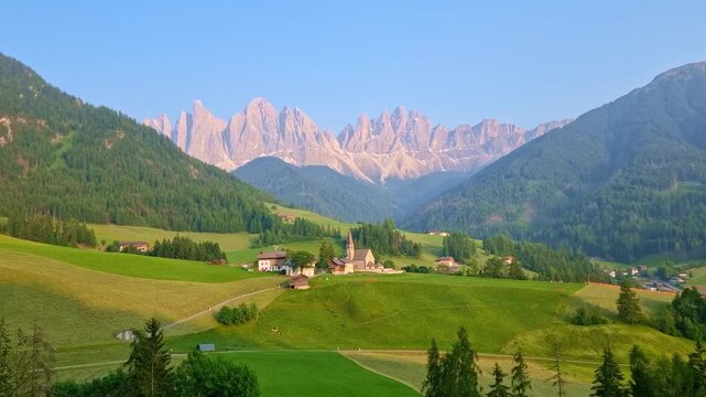 Iconic landscape in Val di Funes, Italy, with famous Santa Maddalena village and Odle mountains in the background, in Dolomites, South Tyrol, at sunset, in springtime. Timelapse