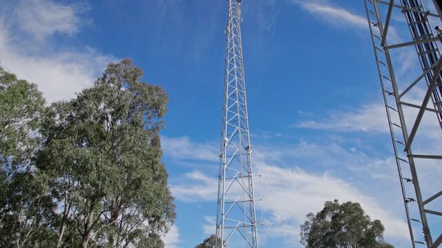 Tall telecom tower rising above bushland at remote mining site, supporting wireless communication and network infrastructure in rural Australia under blue sky.