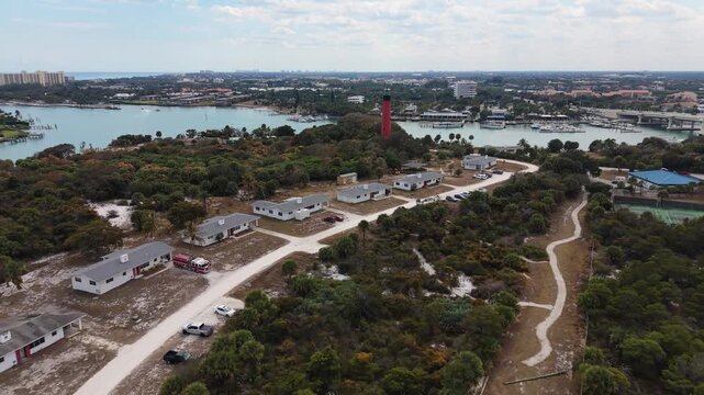 Drone flying south past the Jupiter Lighthouse in Jupiter Florida toward DuBois Park and over the Jupiter Inlet, Loxahatchee River showing the marinas and the Atlantic Ocean in the distance.