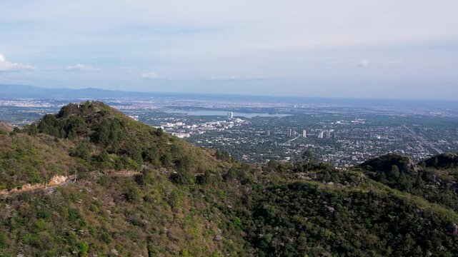 Wide view of Islamabad cityscape from Margalla Hills with green slopes and distant buildings, Pakistan