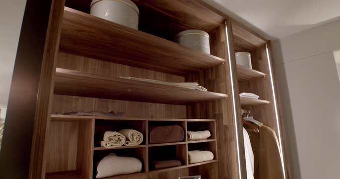Modern luxury wooden walk-in closet with integrated LED lighting and organized shelving system