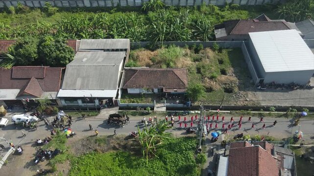 Aerial view of a busy village street with houses and rice fields in Indonesia, 4K footage.