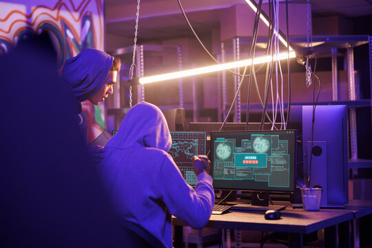 Hackers getting access denied message on computer screen while hacking server. Two criminals in hoods breaking into network system unsuccessfully while doing illegal activity