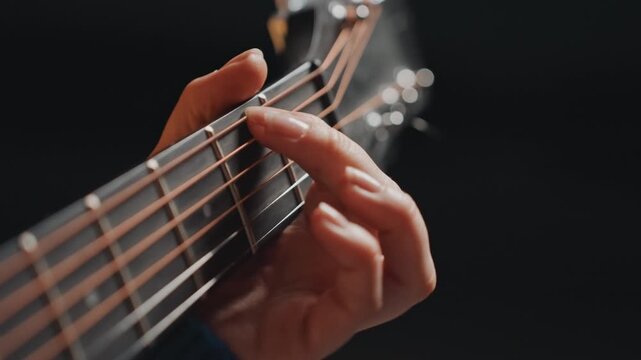 Closeup acoustic guitar fretboard showing precise finger placement during quiet fingerstyle practice, warm studio glow, shallow depth, dark background, solo musician concentrating on chord transitions