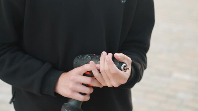 Testing outdoors carefully. Man manipulates drill bit carefully outside during daylight. Male individual skillfully handles drill bit outside in natural daylight for learning purposes