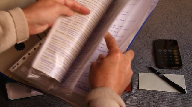 Pasar hojas, hojear apuntes y revisar papeles y ojear documentos de carpetas y archivadores con calculadora, boli y nota