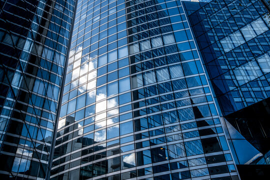 Modern skyscraper glass facade with upward perspective and sky reflection presenting office building architecture in a clean urban corporate mood