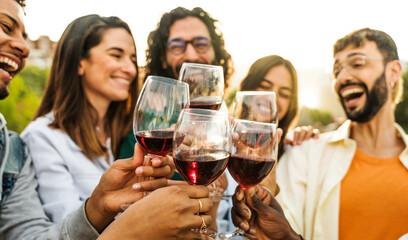 Fototapeta premium Young people toasting red wine glasses at farm house vineyard countryside