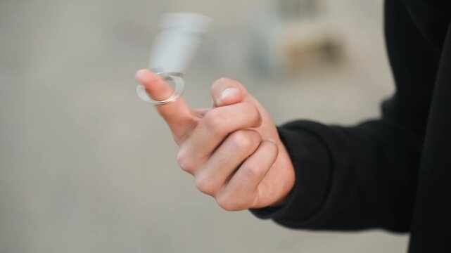 Hand skillfully flips. Enthusiastic Caucasian hand energetically juggles key on ground surface. Precise and vigorous motion of hand flipping key fob onto concrete floor with assurance