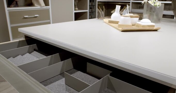 Modern walk-in closet island with open drawer and organizational dividers in a luxury showroom