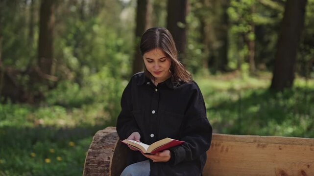 Young woman reading book in forest park