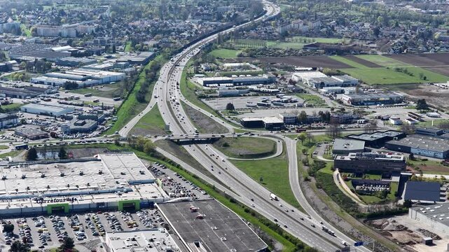 Aerial view of Carrefour Shopping Centre and a highway interchange, contrasting urban development with green spaces, Sausheim, Grand Est, France.