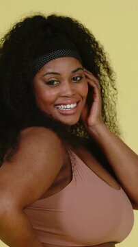 Vertical video: Facing cam, smiling woman rotating fixing hair posing with pale wall headband jeans