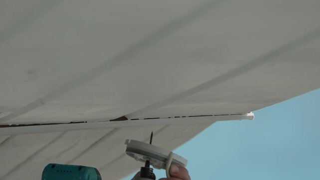 Drill, screw, ceiling, person drilling screw into white ceiling panels with power tool.