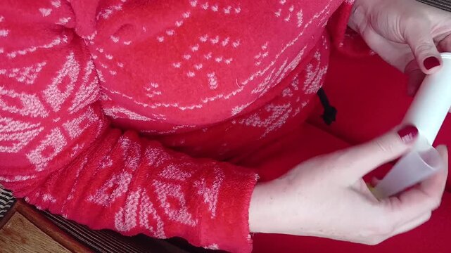 Stock video of female hands with red manicure opening pills and pouring them into hand, woman seems to hesitate to take or not take medicine, health theme. Woman in red clothes.