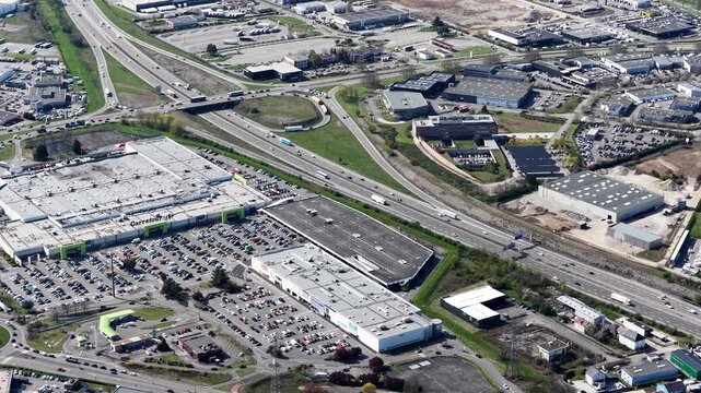 Aerial view of the sprawling Carrefour shopping mall complex alongside a busy highway with cars and trucks, Sausheim, Grand Est, France.