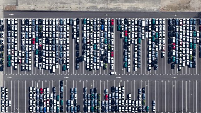 Aerial view of orderly rows of parked cars, a symphony of whites, grays and occasional splashes of color creating a mesmerizing grid, Sausheim, Grand Est, France.